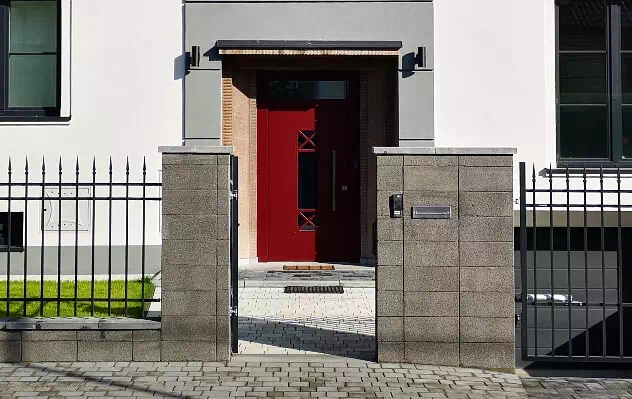 Widok elewacji domu jednorodzinnego z czerwonymi drzwiami zewnętrznymi
