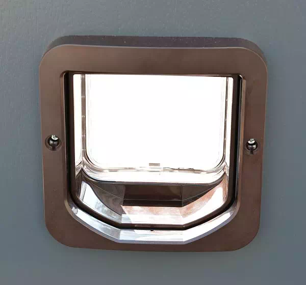 Widok zewnętrznej strony klapki dla kota zamontowanej w drzwiach zewnętrznych.