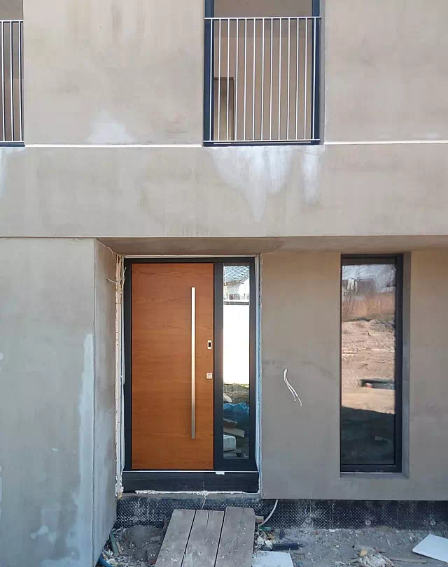 Widok elewacji domu z zamontowanymi drzwiami wzór 500B wymalowanymi w kolorze winchester+antracyt.