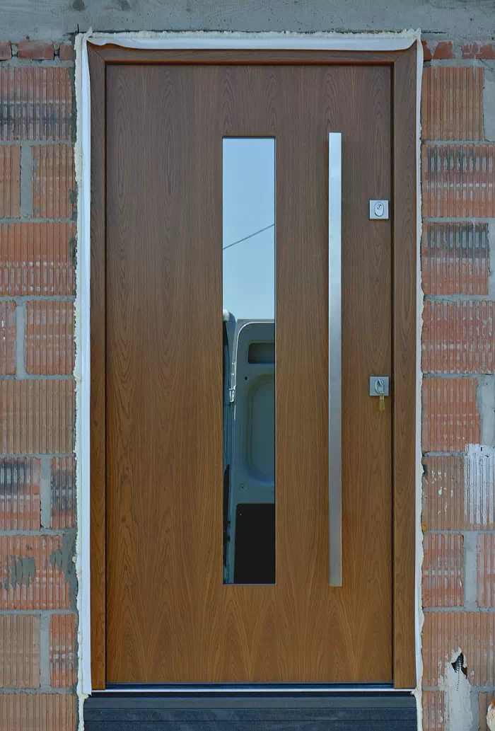 Widok elewacji domu z zamontowanymi drzwiami wzór 454,15 wymalowanymi w kolorze ciemny dąb.