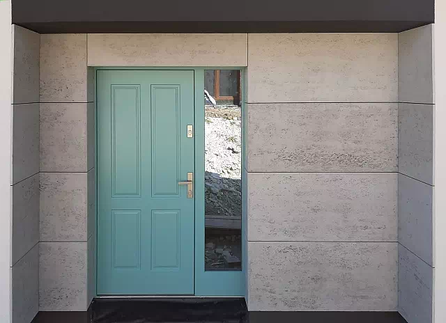 Widok elewacji domu z zamontowanymi drzwiami wzór 534,9 wymalowanymi w kolorze turkusowe.