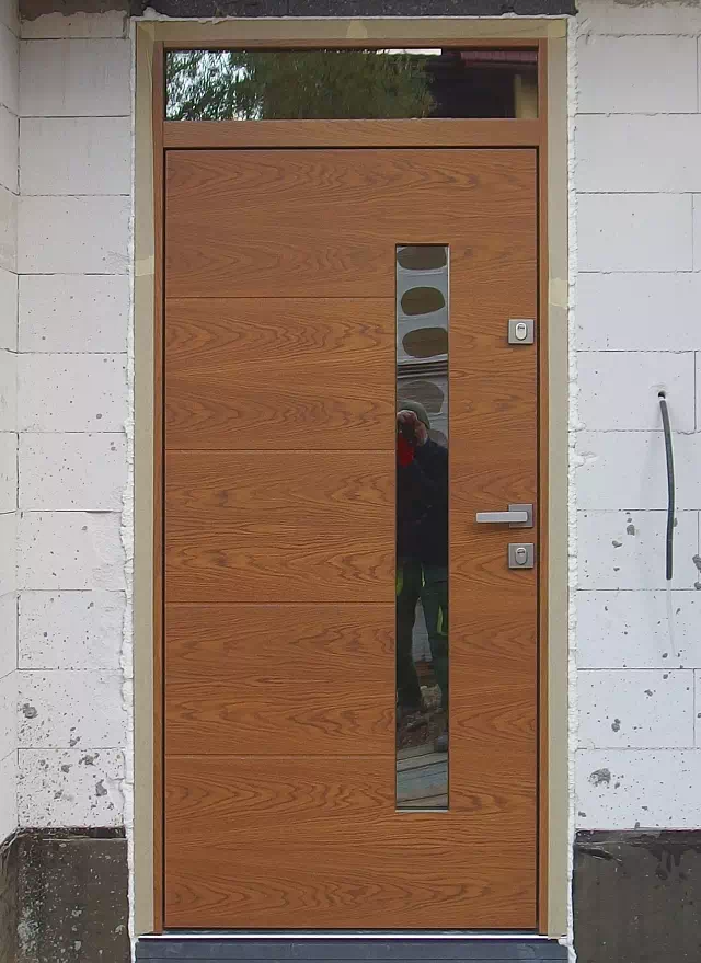 Widok elewacji domu z zamontowanymi drzwiami wzór 417,13 wymalowanymi w kolorze ciemny dąb.