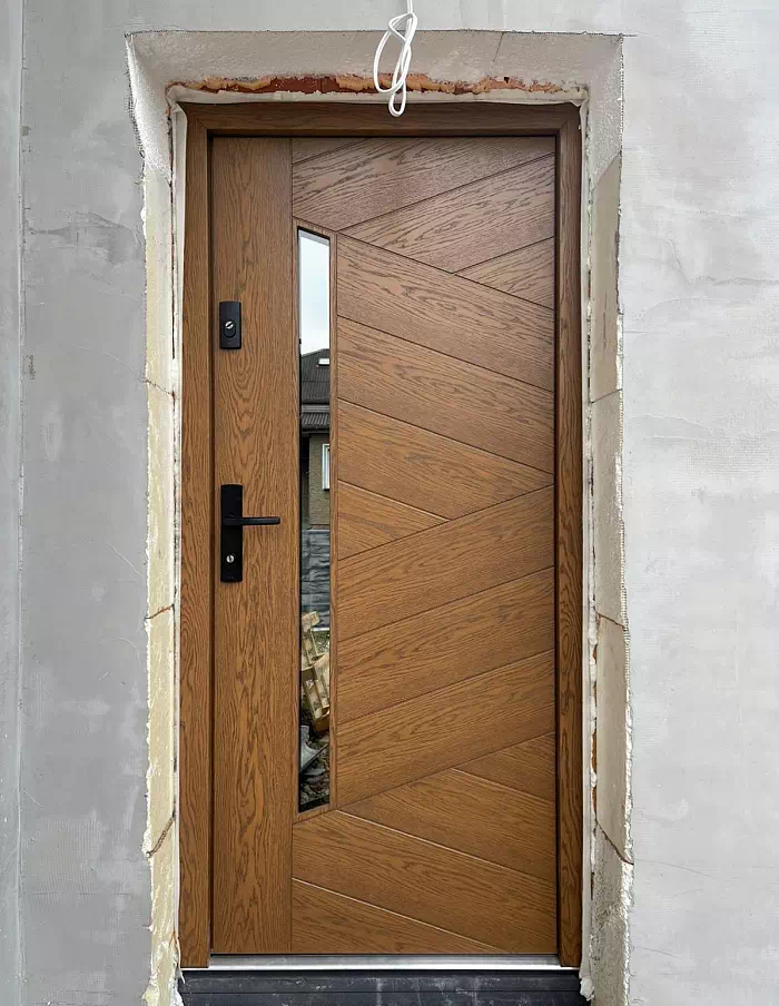 Widok elewacji domu z zamontowanymi drzwiami wzór 430,15 wymalowanymi w kolorze ciemny dąb.