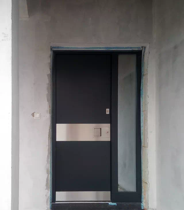 Widok elewacji domu z zamontowanymi drzwiami wzór 500C wymalowanymi w kolorze antracyt.