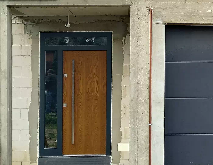 Widok elewacji domu z zamontowanymi drzwiami wzór 500C wymalowanymi w kolorze ciemny dąb + antracyt.