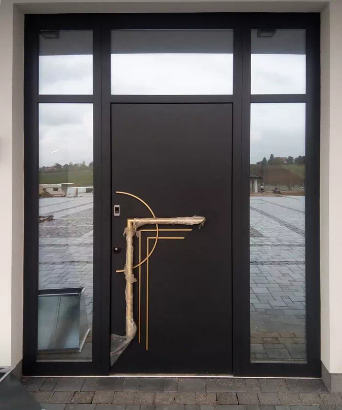 Widok elewacji domu z zamontowanymi drzwiami wzór 500C wymalowanymi w kolorze czarne.