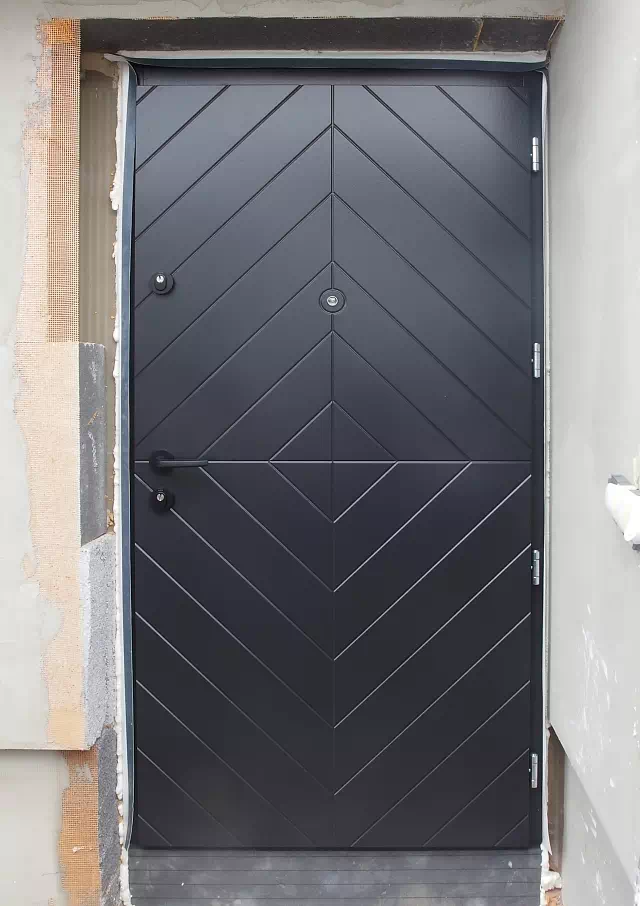 Widok elewacji domu z zamontowanymi drzwiami wzór 542,1w wymalowanymi w kolorze czarne.