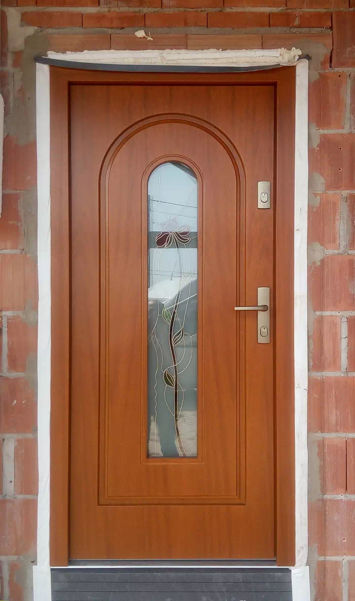 Widok elewacji domu z zamontowanymi drzwiami wzór 571s2+ds56 wymalowanymi w kolorze złoty dąb.