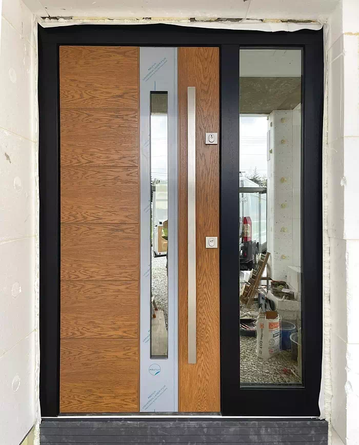 Widok elewacji domu z zamontowanymi drzwiami wzór 475,4 wymalowanymi w kolorze złoty dąb + czarne.