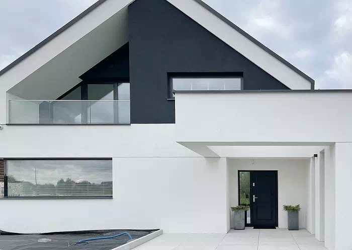 Widok elewacji domu z zamontowanymi drzwiami wzór 535,5 wymalowanymi w kolorze czarne.