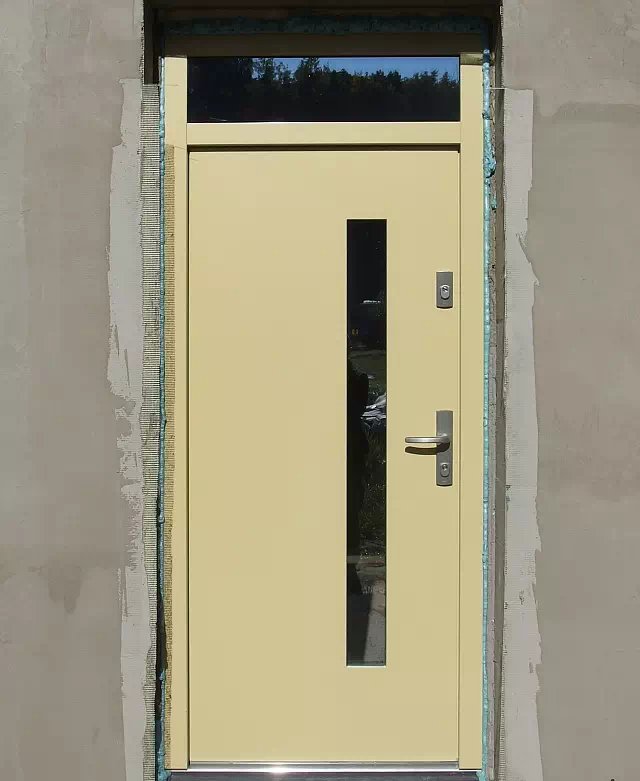 Widok elewacji domu z zamontowanymi drzwiami wzór 427,11 wymalowanymi w kolorze zółte.