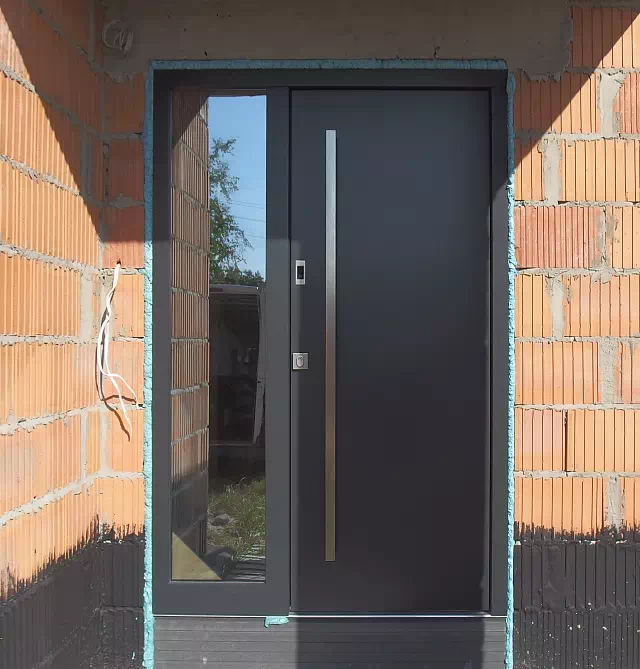 Widok elewacji domu z zamontowanymi drzwiami wzór 500C wymalowanymi w kolorze antracytowe.
