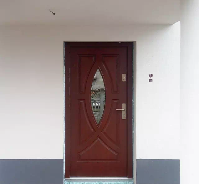 Widok elewacji domu z zamontowanymi drzwiami wzór 503,2 wymalowanymi w kolorze teak.