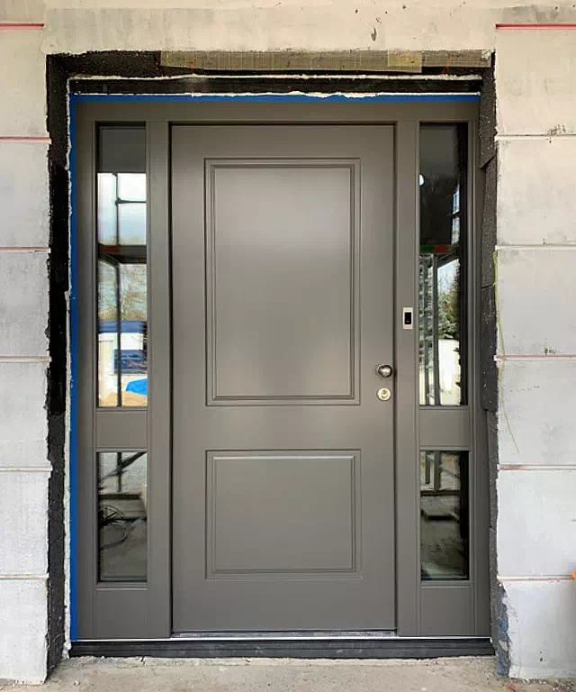Widok elewacji domu z zamontowanymi drzwiami wzór 535,6 wymalowanymi w kolorze szare.
