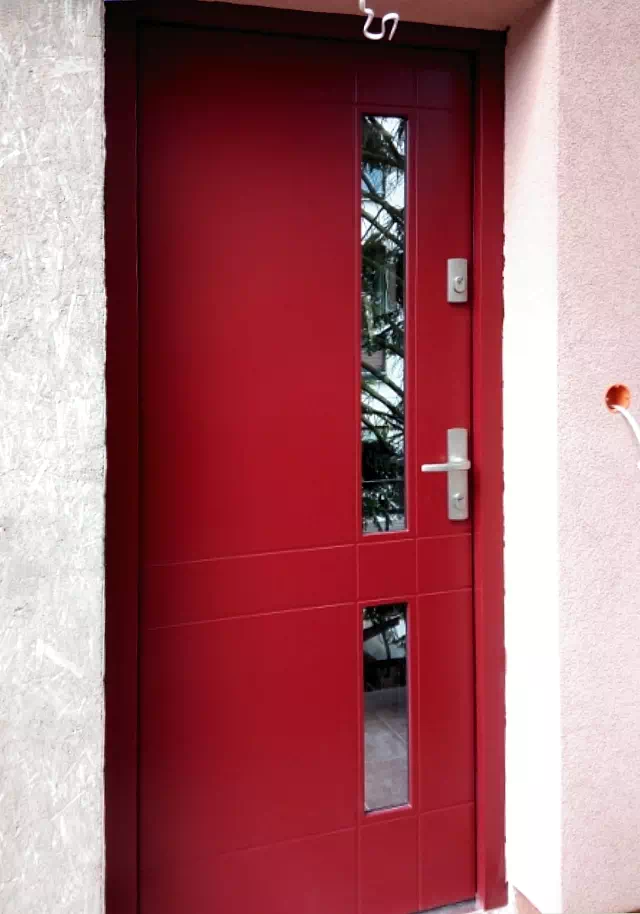 Widok elewacji domu z zamontowanymi drzwiami wzór 685,4 wymalowanymi w kolorze czerwone.