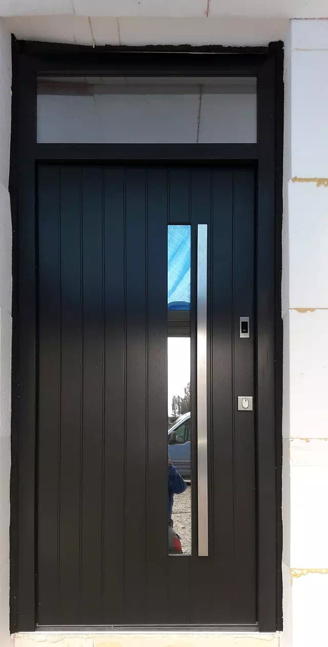 Widok elewacji domu z zamontowanymi drzwiami wzór 689,7s1 wymalowanymi w kolorze czarne.