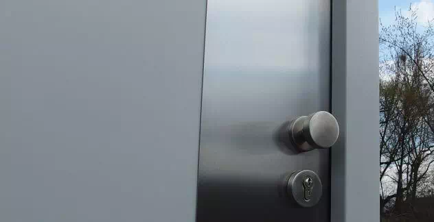 fragment drzwi zewnętrznych z blachą inox i gałką obrotową