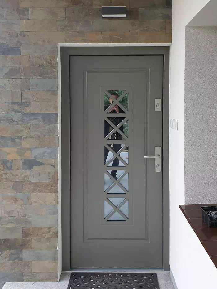 Widok elewacji domu z zamontowanymi drzwiami wzór 546,1 wymalowanymi w kolorze szare.
