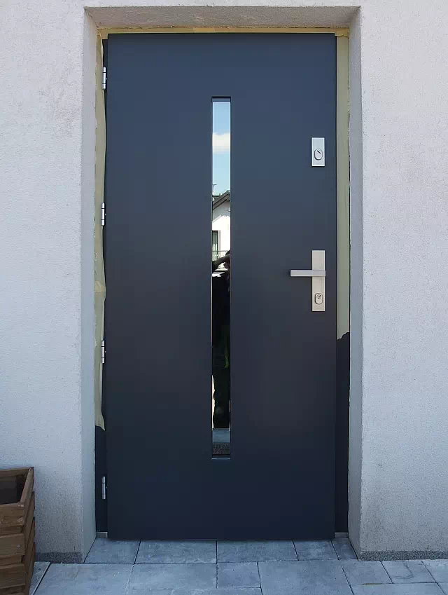Widok elewacji domu z zamontowanymi drzwiami wzór 454,11 wymalowanymi w kolorze antracyt.