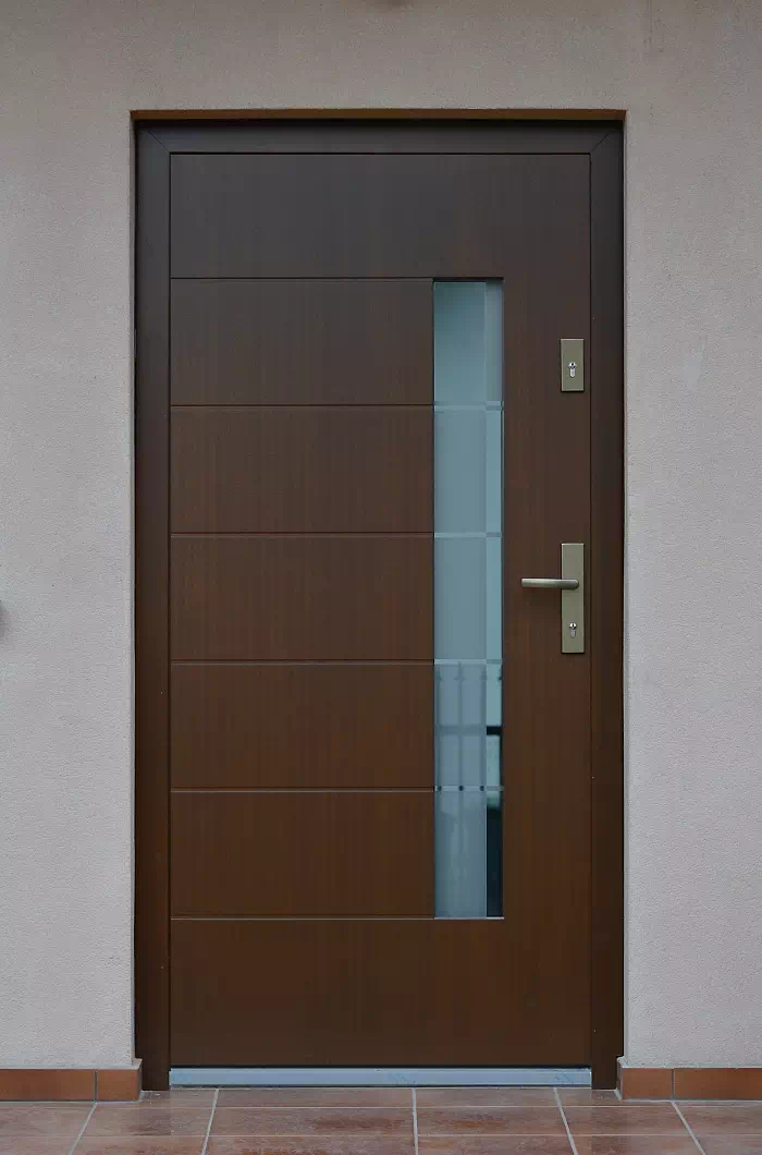 Widok elewacji domu z zamontowanymi drzwiami wzór 478,5+ds11 wymalowanymi w kolorze orzech.