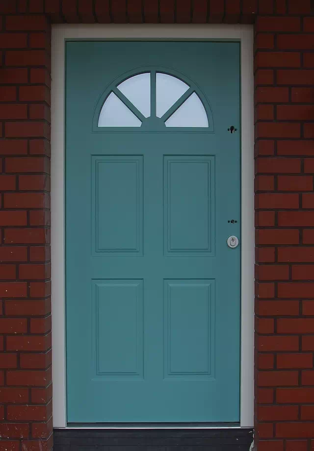 Widok elewacji domu z zamontowanymi drzwiami wzór 506,2 wymalowanymi w kolorze zielone.
