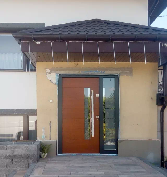 Widok elewacji domu z zamontowanymi drzwiami wzór 476,4+ds1 wymalowanymi w kolorze ciemny dąb + antracyt.