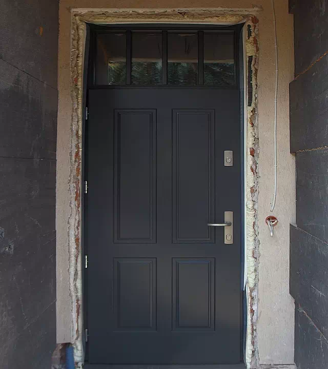 Widok elewacji domu z zamontowanymi drzwiami wzór 534,9 wymalowanymi w kolorze antracytowe.