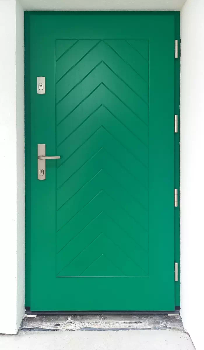 Widok elewacji domu z zamontowanymi drzwiami wzór 543,2 wymalowanymi w kolorze zielone.