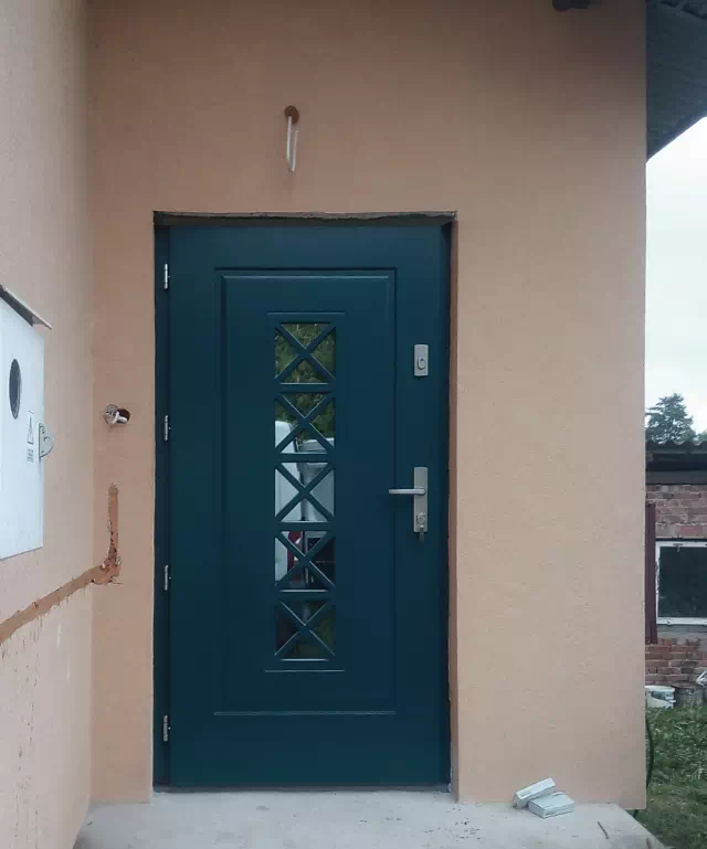 Widok elewacji domu z zamontowanymi drzwiami wzór 546,1 wymalowanymi w kolorze antracyt.