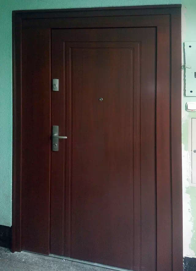 Widok elewacji domu z zamontowanymi drzwiami wzór 642,1 wymalowanymi w kolorze orzech.